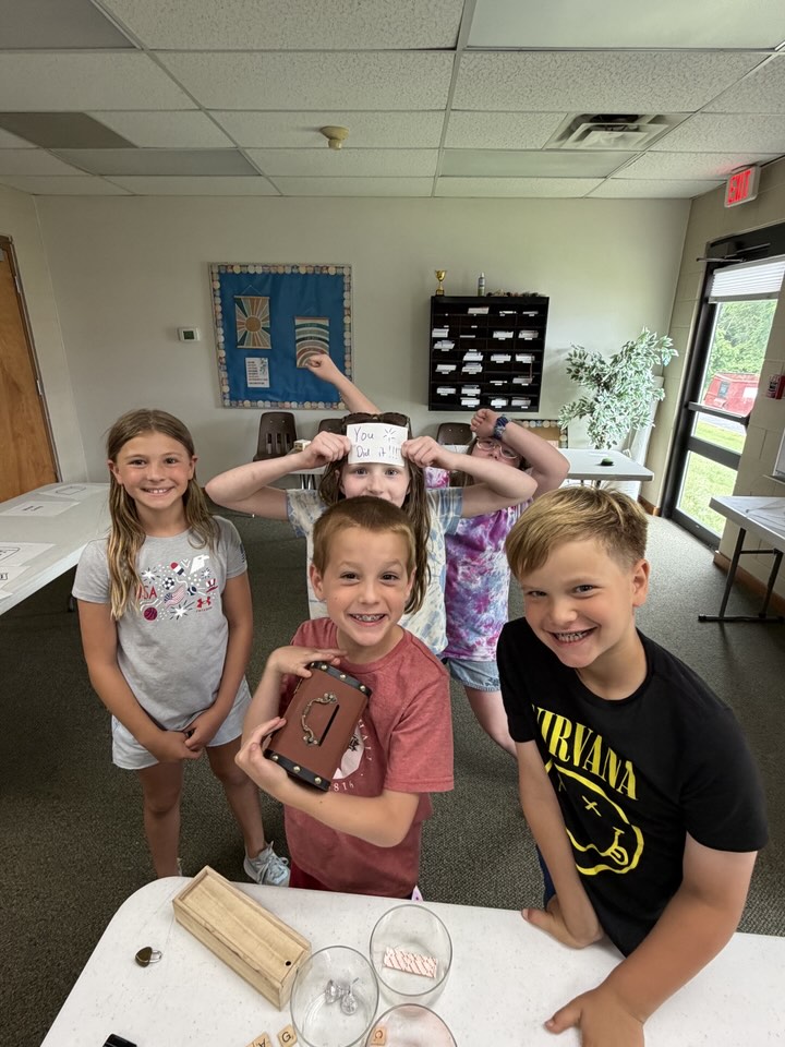 Campers cheering and holding a You Did It sign after opening a locked puzzle box