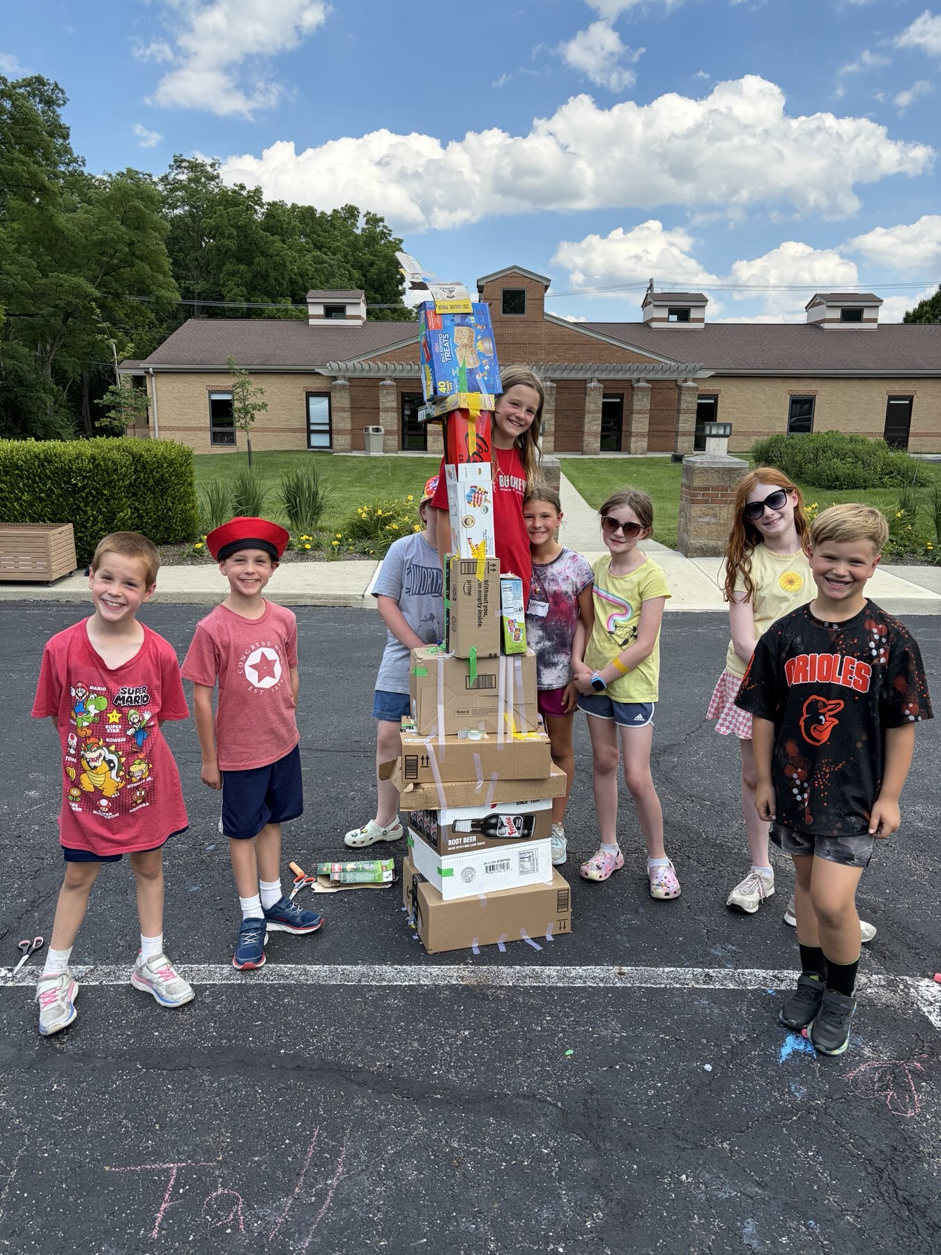 Campers standing next to a tall tower they built from cardboard boxes