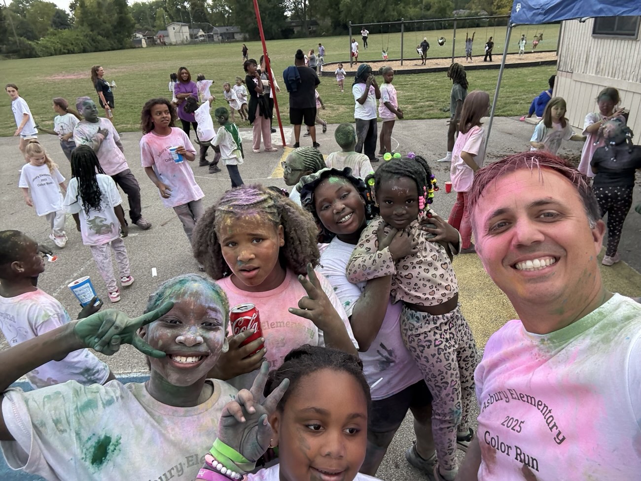 Michael taking a selfie with smiling, color-dusted students at a school color run
