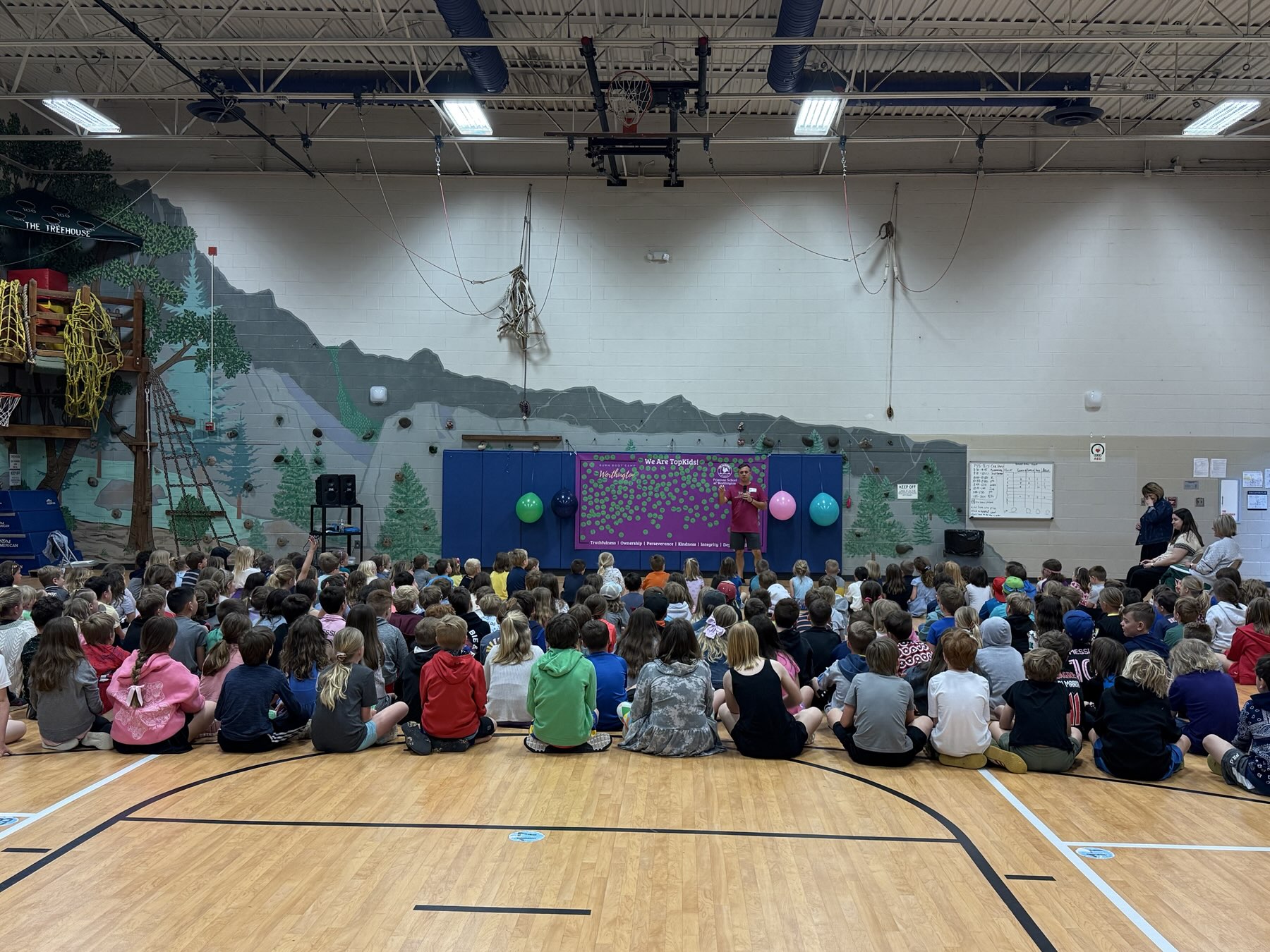 Students seated in a school gym watching a TopKid presentation